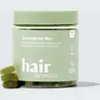 Grønn boks med Hairlust Hair Formula Gummies for Men og tre grønne vingummier ved siden av