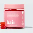 Rosa boks med Hairlust Hair Formula Gummies for Women og oransje vingummier som helles ut i en glassbolle