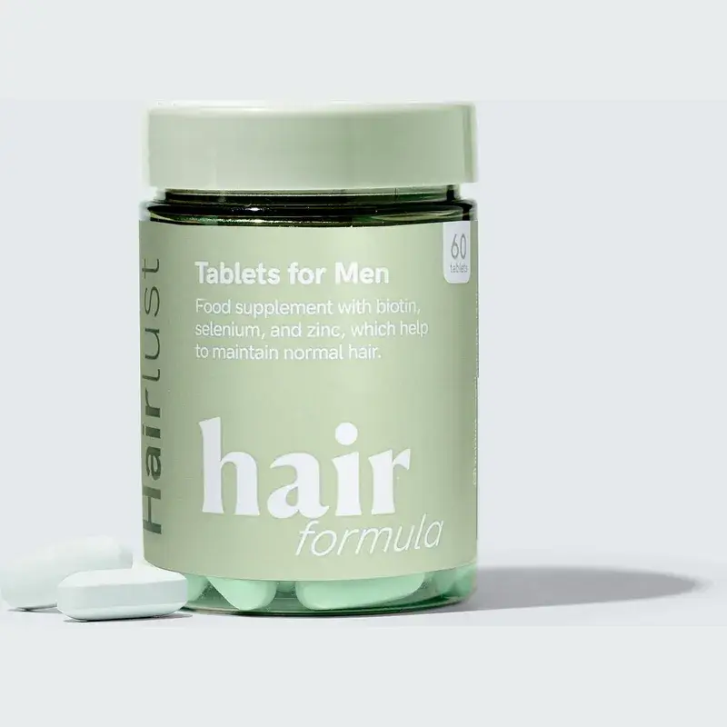 Grønn boks med Hairlust Hair Formula Tablets for Men og to lyse grønne tabletter foran